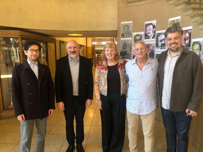 Professor Linda Mulcahy with Chilean Scholars Professor Linda Mulcahy standing with four Chilean scholars indoors, posing for a group photo. They are in a hallway with posters in the background, smiling for the camera.